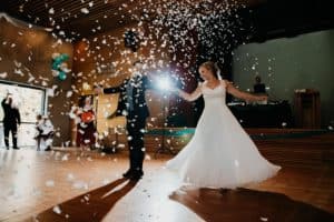 Hochzeitstanz Brautpaar Hand in Hand Kleid der Braut fliegt durch Luft Konfetti
