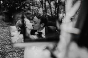 Brautpaar küsst sich im Oldtimer nur sichtbar durch Spiegelung im Seitenspiegel