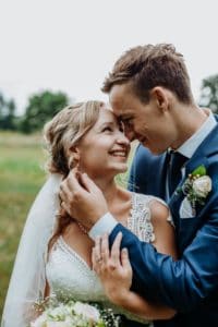 Brautpaar steht eng zusammen Bräutigam streichelt Hals der Braut tiefer Blick beide lächeln