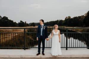 Brautpaar Hand in Hand auf einer Brücke beide schauen in unterschiedliche Richtungen