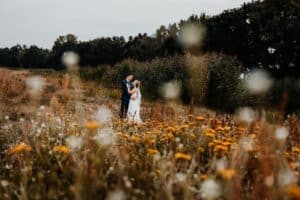 Brautpaar hält sich fest steht in weiß gelber Wildblumenwiese