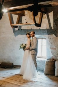 Brautpaar steht in alter Mühle nebeneinander und kuschelt