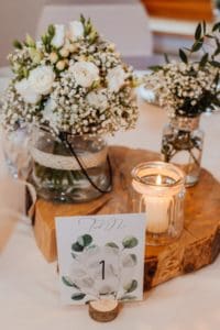 Blumendekoration Schleierkraut weiße Rosen Kerzen Baumscheibe Tischnummer