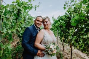 Bräutigam umarmt Braut Brautstrauß Weinberg Weinanlage