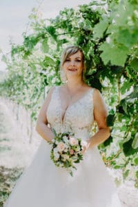 Braut lächelt mit Brautstrauß Weinberg Weinanlage