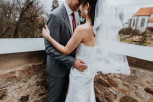 Braut und Bräutigam umarmen sich Schleier Anzug Kirchenmauer